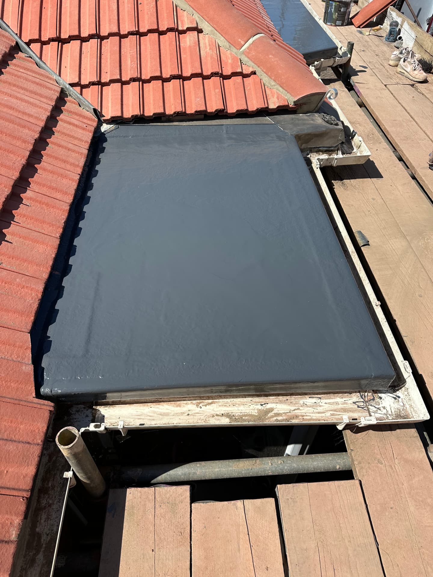 New grey GRP fibreglass flat roof beside red pitched tiles