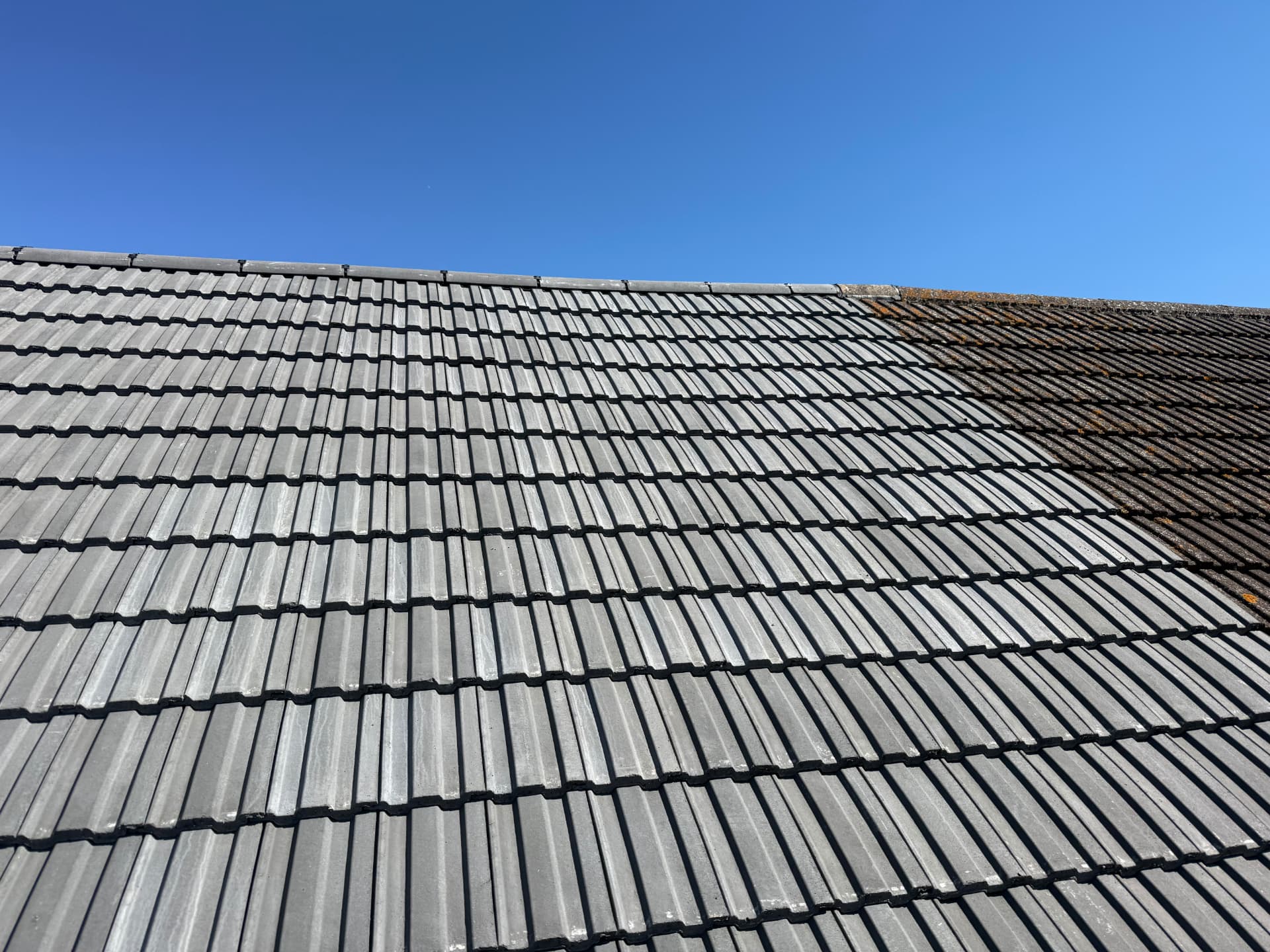 Grey tiled roof part-way through a re-roof